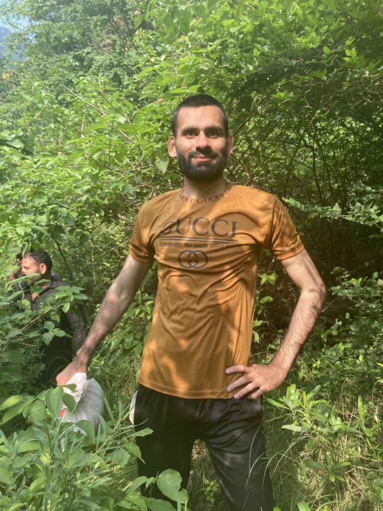 A man standing on a hiking track in the middle greenery, in the sunlight of afternoon